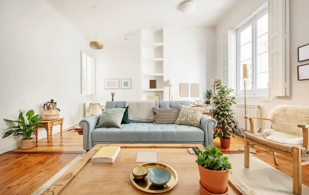 Reforma integral de salón con suelo de madera original, estantería de obra blanca y paredes lisas en Alicante
